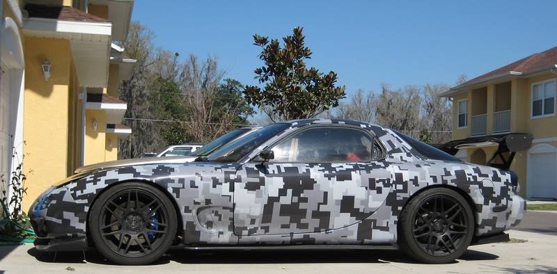 Side profile of the V1 RX-7 in white and black digicamo, parked in a driveway